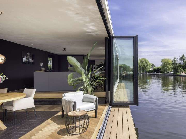Glas-Faltwand von Solarlux öffnet das Hausboot zum Wasser hin auf voller Breite
